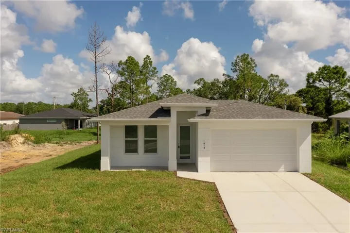View of front facade featuring a front yard and a garage