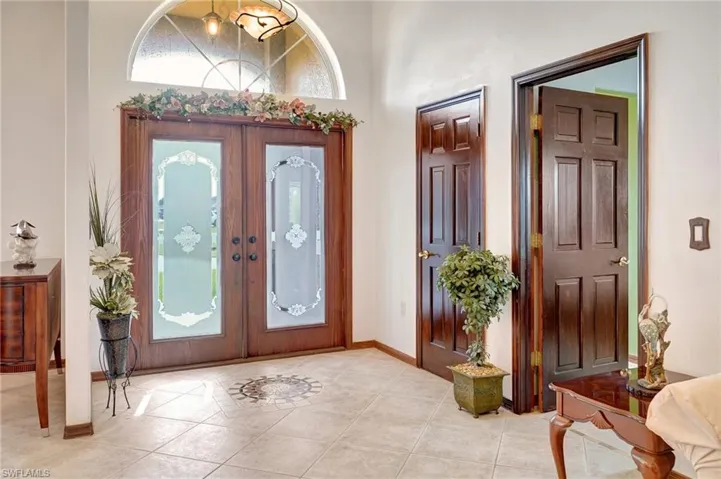 Entrance foyer with light tile patterned floors, french doors, and a towering ceiling