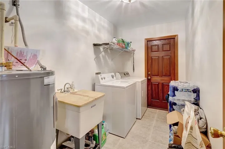 Laundry area featuring water heater, independent washer and dryer, and sink