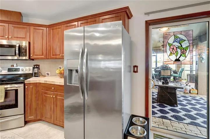 Kitchen with tasteful backsplash, light tile patterned floors, and appliances with stainless steel finishes