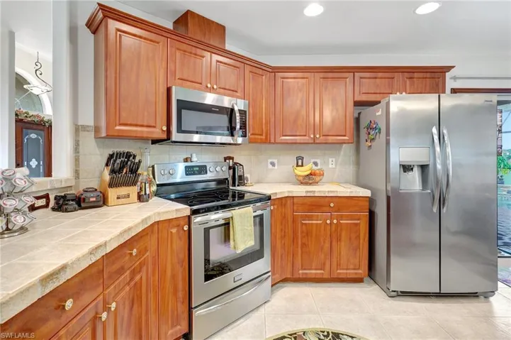 Kitchen featuring light tile patterned floors, appliances with stainless steel finishes, tile countertops, and tasteful backsplash