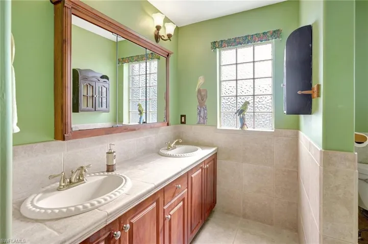 Bathroom with tile patterned flooring, a healthy amount of sunlight, tile walls, and vanity