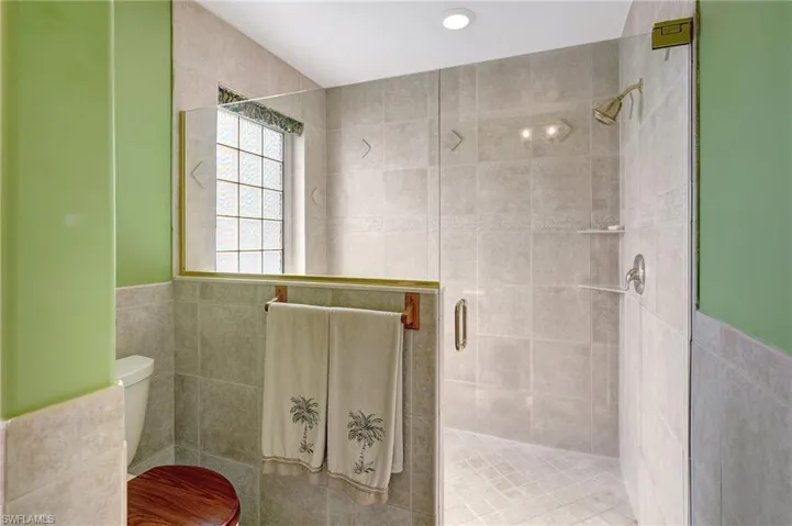 Bathroom with toilet, tile walls, and a shower with door