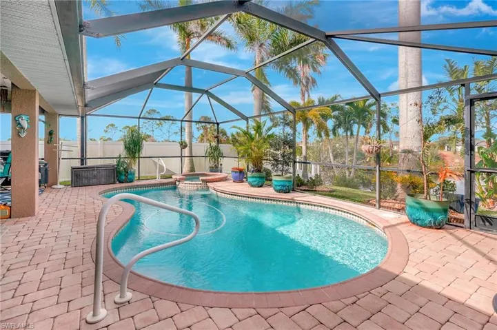 View of swimming pool featuring glass enclosure, an in ground hot tub, and a patio