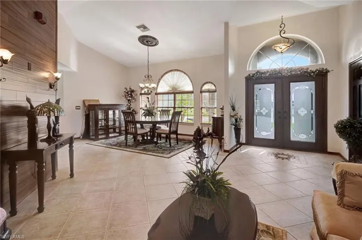 Tiled foyer entrance with a towering ceiling, a notable chandelier, and french doors
