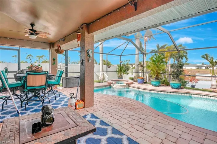View of swimming pool with a lanai, ceiling fan, an in ground hot tub, and a patio