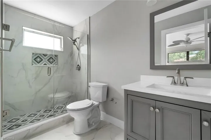 Bathroom with vanity, a marble finish shower, marble finish floors, and ceiling fan