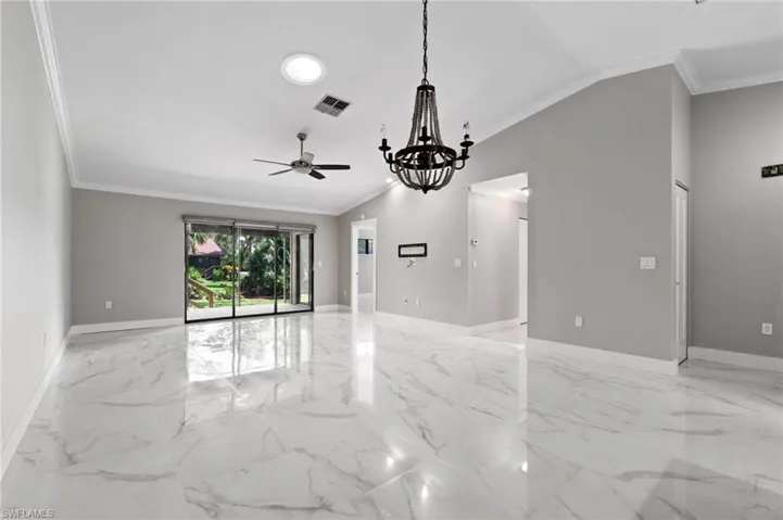 Empty room with crown molding, ceiling fan, light marble finish flooring, a chandelier, and lofted ceiling