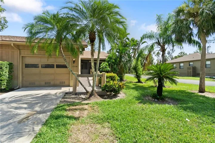 Ranch-style home with an attached garage, driveway, a front lawn, and stucco siding