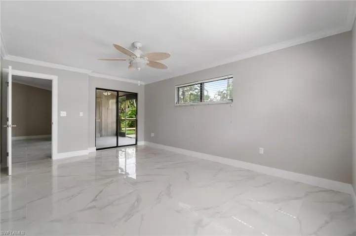 Empty room featuring ceiling fan, light marble finish flooring, and ornamental molding