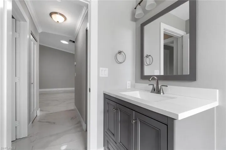 Bathroom with marble finish flooring, ornamental molding, and vanity