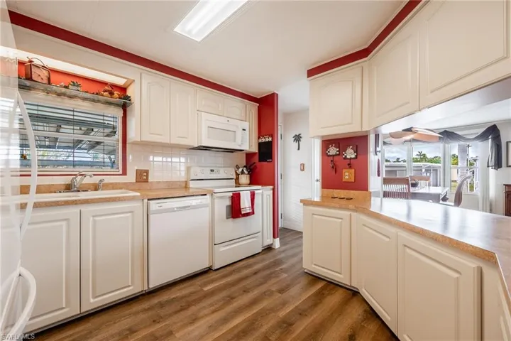 Kitchen with white appliances, light countertops, a sink, and wood finished floors