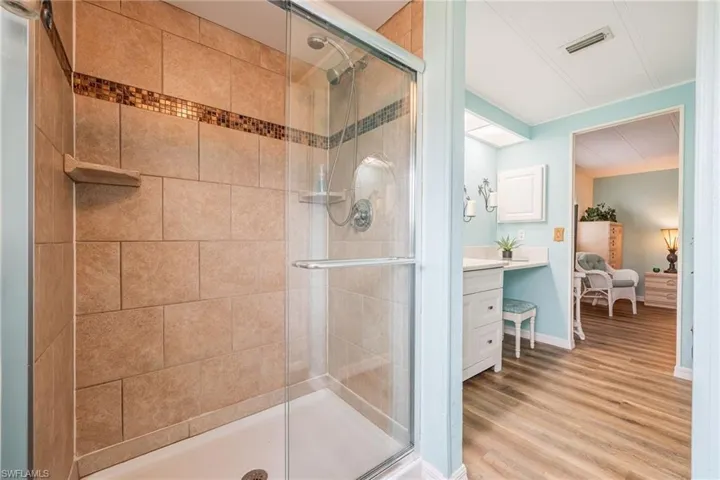 Ensuite bathroom featuring ensuite bathroom, vanity, visible vents, wood finished floors, and a stall shower
