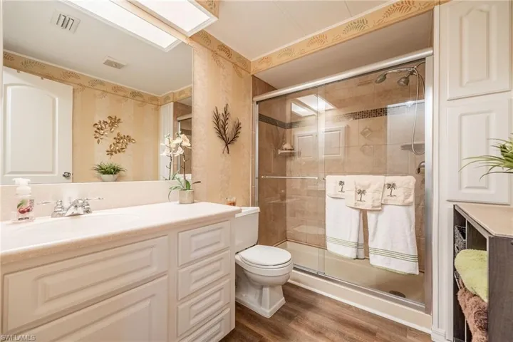 Bathroom featuring visible vents, a shower stall, vanity, and wood finished floors