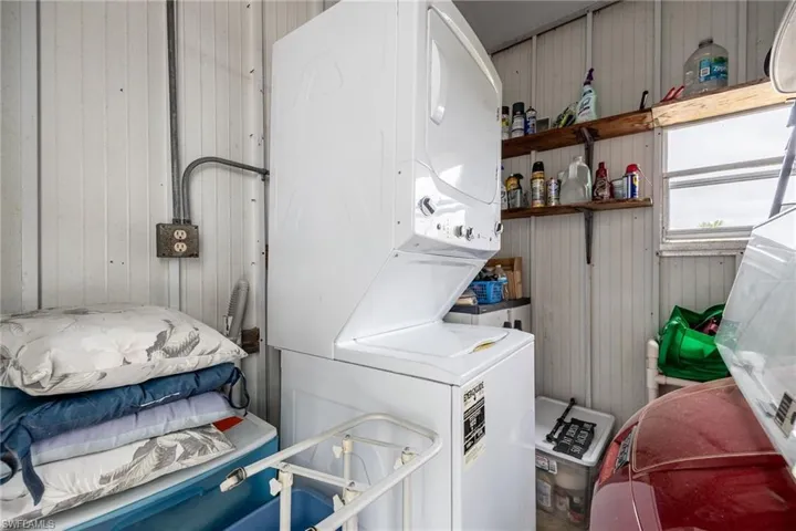 Laundry room with wooden walls, stacked washer / dryer, and laundry area