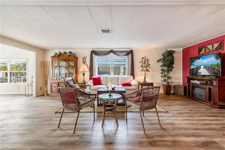 Living area with a glass covered fireplace, visible vents, and wood finished floors