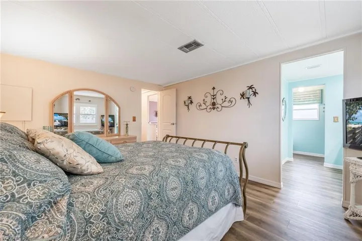 Bedroom with arched walkways, wood finished floors, baseboards, and visible vents
