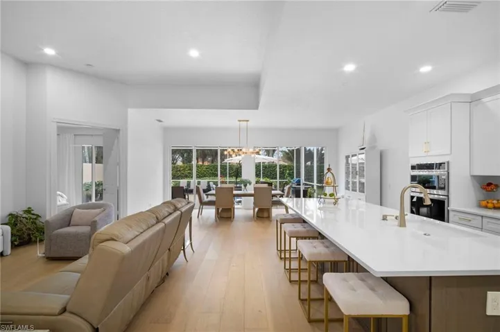 Kitchen featuring a kitchen bar, white cabinetry, light wood flooring, open floor plan, and recessed lighting
