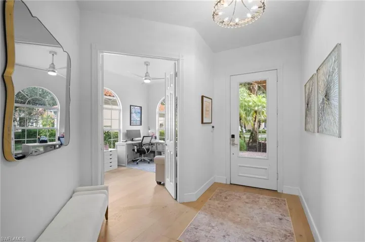 Entryway with light wood finished floors and a chandelier
