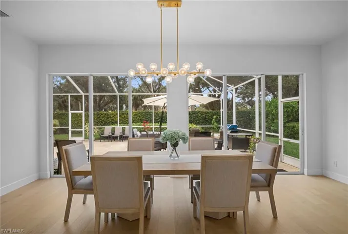 Dining area featuring a sunroom, a chandelier, and light wood finished floors
