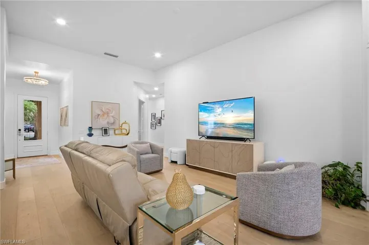 Living area featuring light wood finished floors, recessed lighting, and a chandelier