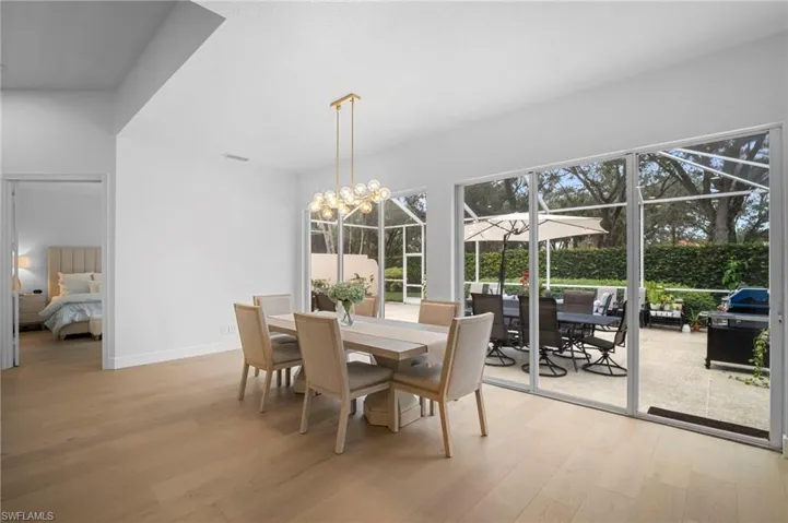 Dining room with light wood finished floors, a sunroom, and a chandelier
