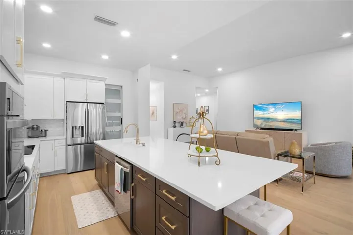 Kitchen featuring a kitchen breakfast bar, light wood finished floors, white cabinets, open floor plan, and recessed lighting