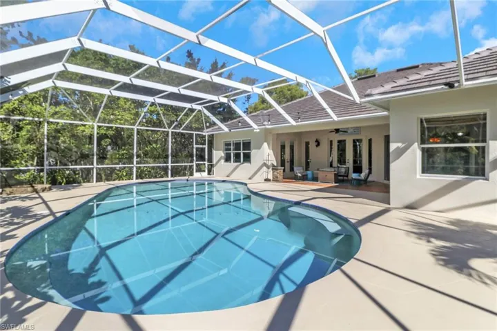 Outdoor pool featuring glass enclosure, a ceiling fan, a patio area, a sunroom, and french doors