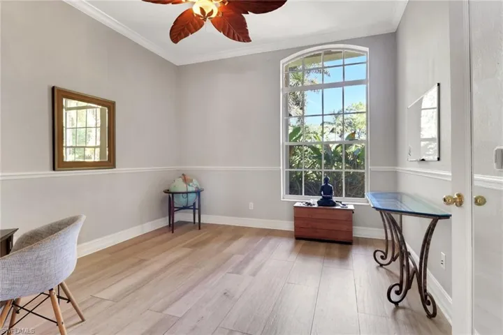 Office area with crown molding, light wood-style floors, and ceiling fan