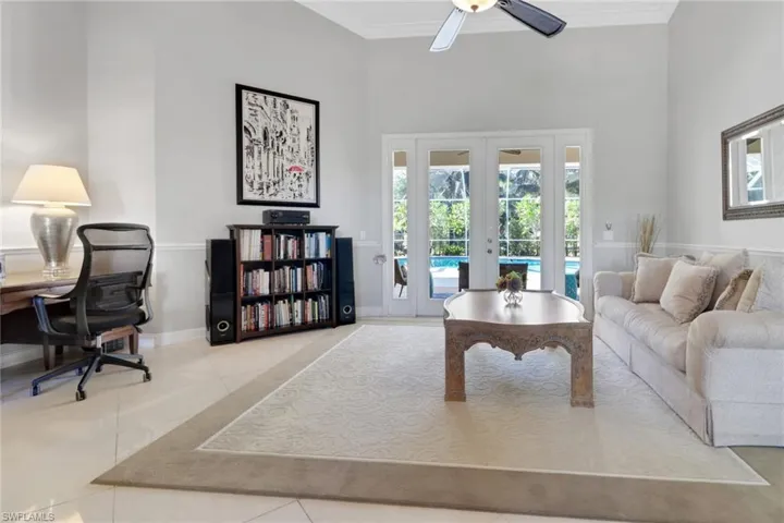 Tiled living area with french doors, ornamental molding, a towering ceiling, and an office area