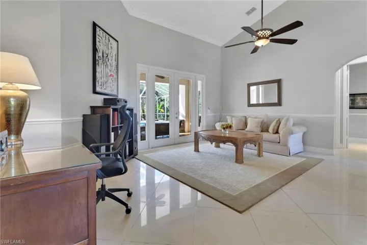 Living room with french doors, high vaulted ceiling, light tile patterned floors, arched walkways, and crown molding