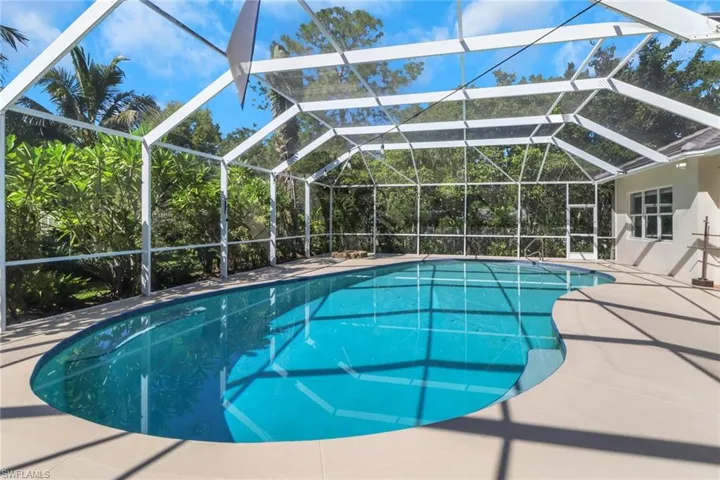 Swimming pool featuring glass enclosure, a sunroom, and a patio