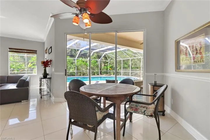 Dining room with crown molding, a sunroom, light tile patterned flooring, and ceiling fan