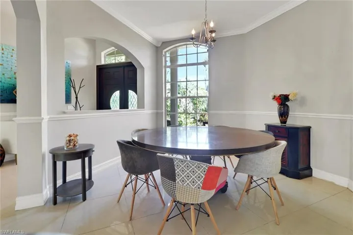 Tiled dining area featuring a chandelier, crown molding, and arched walkways