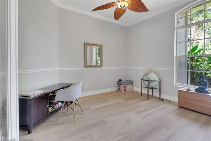 Home office with crown molding, light wood-type flooring, and ceiling fan