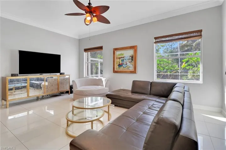 Living area with ornamental molding, tile patterned floors, and ceiling fan