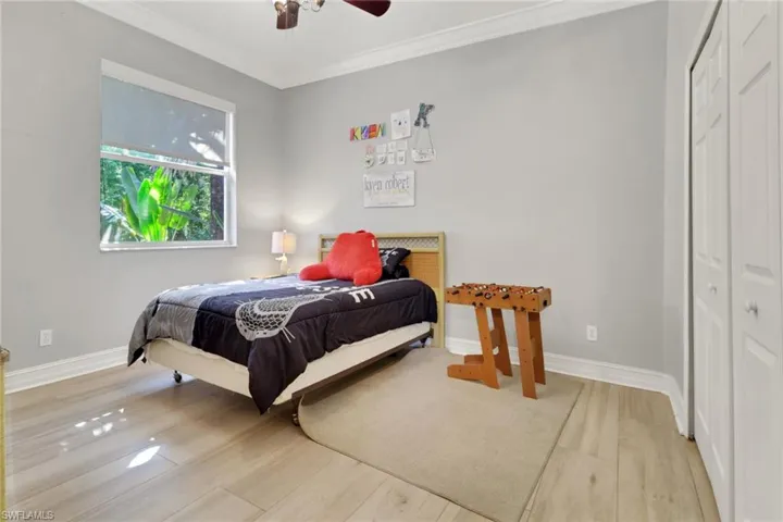 Bedroom featuring crown molding, a closet, light wood finished floors, and a ceiling fan
