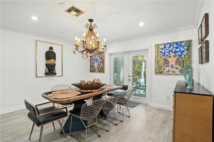 Dining area featuring french doors, a chandelier, light wood finished floors, ornamental molding, and recessed lighting