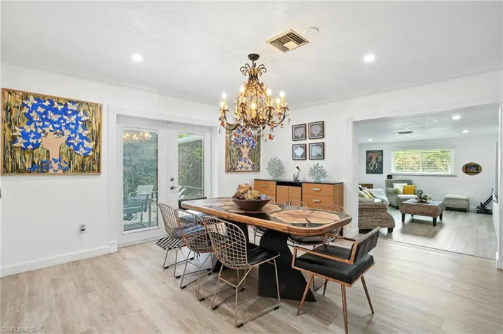 Dining area featuring french doors, light wood-type flooring, a chandelier, recessed lighting, and ornamental molding