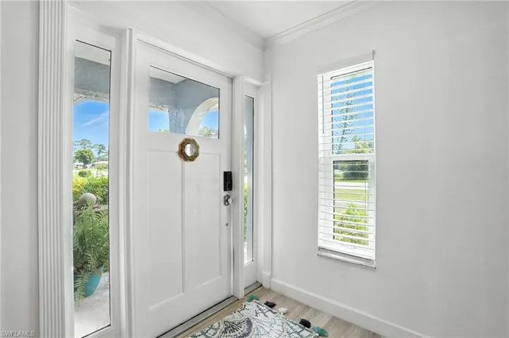 Foyer entrance with crown molding and wood finished floors