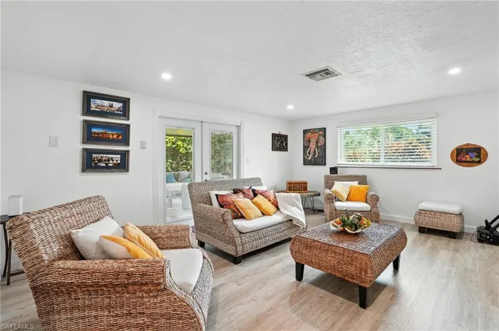 Living area with french doors, healthy amount of natural light, wood finished floors, recessed lighting, and a textured ceiling