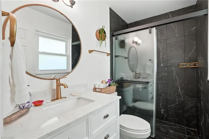 Full bathroom featuring vanity and a marble finish shower