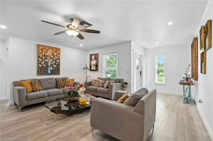 Living area with crown molding, a ceiling fan, plenty of natural light, light wood-style flooring, and recessed lighting