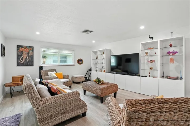 Living room featuring wood finished floors, a textured ceiling, and recessed lighting