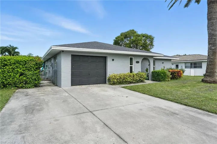 Single story home featuring stucco siding, driveway, an attached garage, a front yard, and a shingled roof