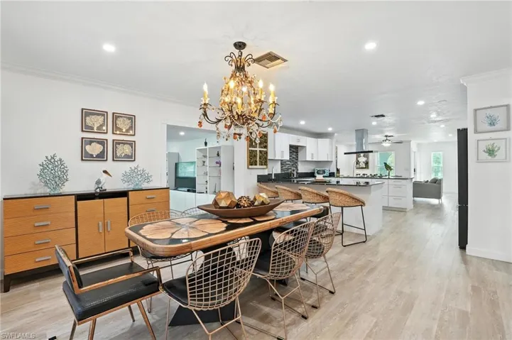 Dining area with recessed lighting, a chandelier, ornamental molding, and light wood-style floors