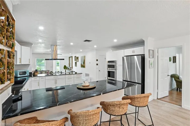Kitchen featuring a peninsula, a kitchen bar, dark countertops, white cabinets, and appliances with stainless steel finishes
