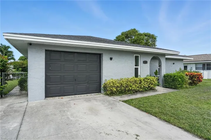 Ranch-style home featuring stucco siding, concrete driveway, a front lawn, and a shingled roof