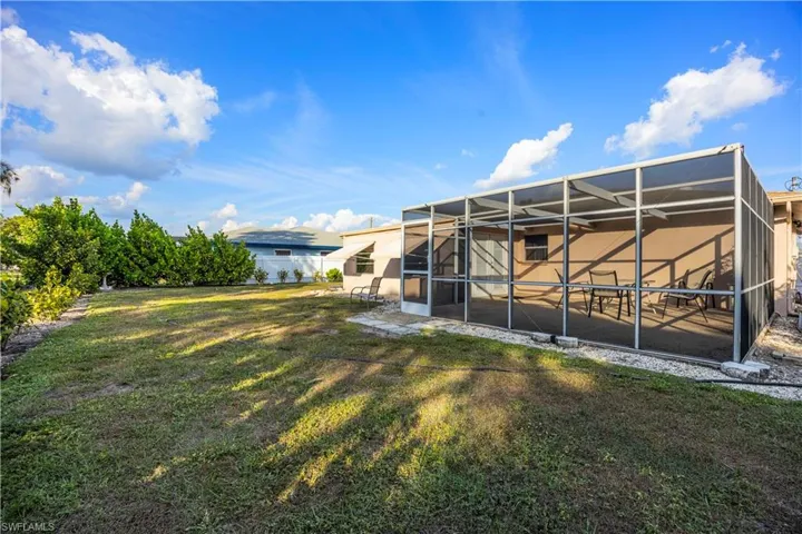 View of green lawn with a sunroom and a lanai