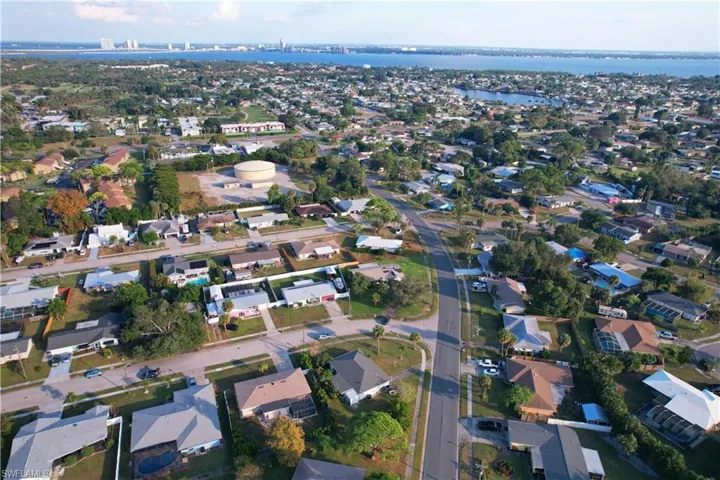 Aerial view of property and surrounding area featuring nearby suburban area and a nearby body of water